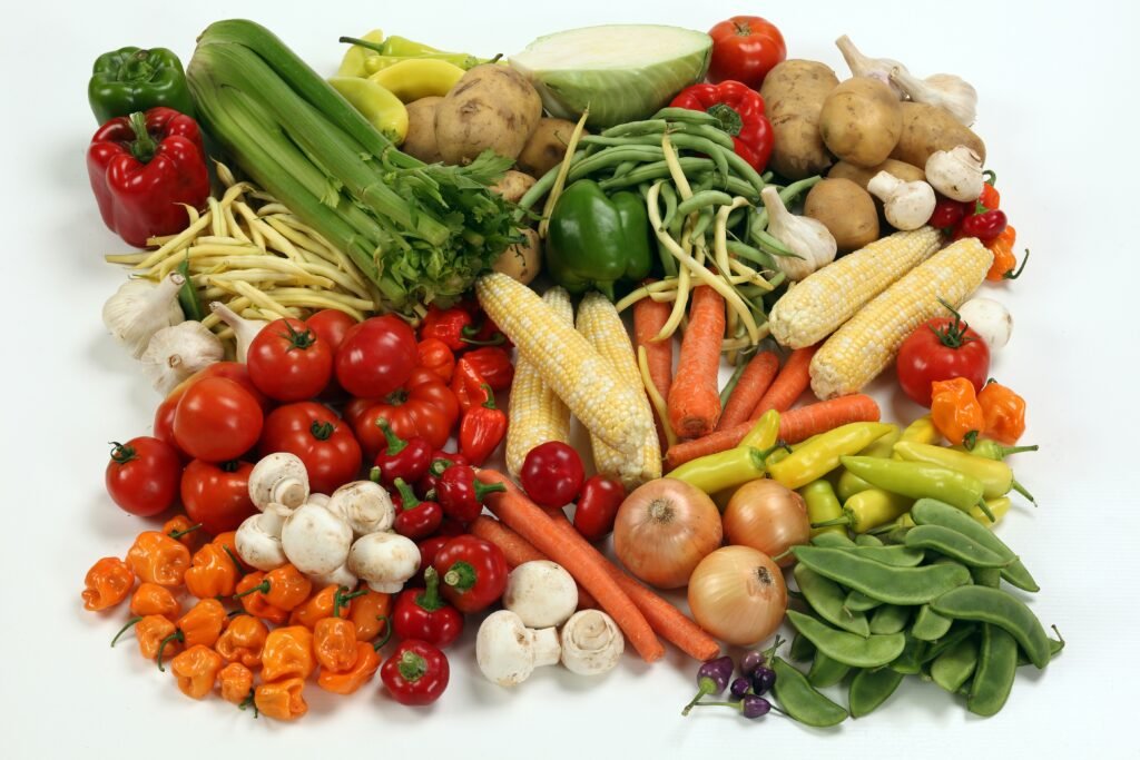 a pile of different types of vegetables on a white surface a pile of different types of vegetables on a white surface