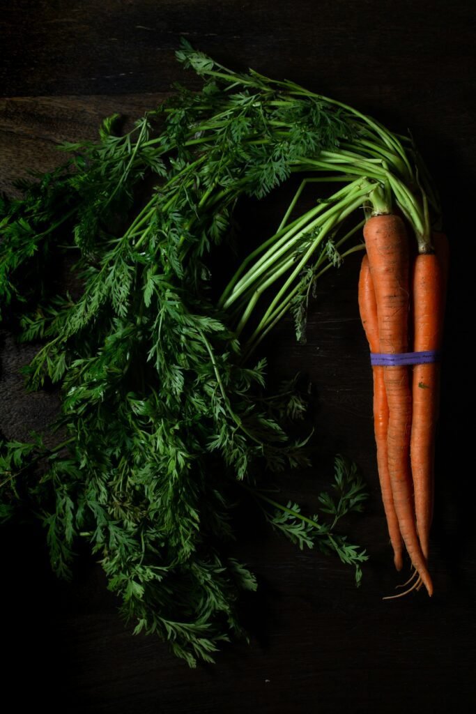 4 carrots on black wooden table